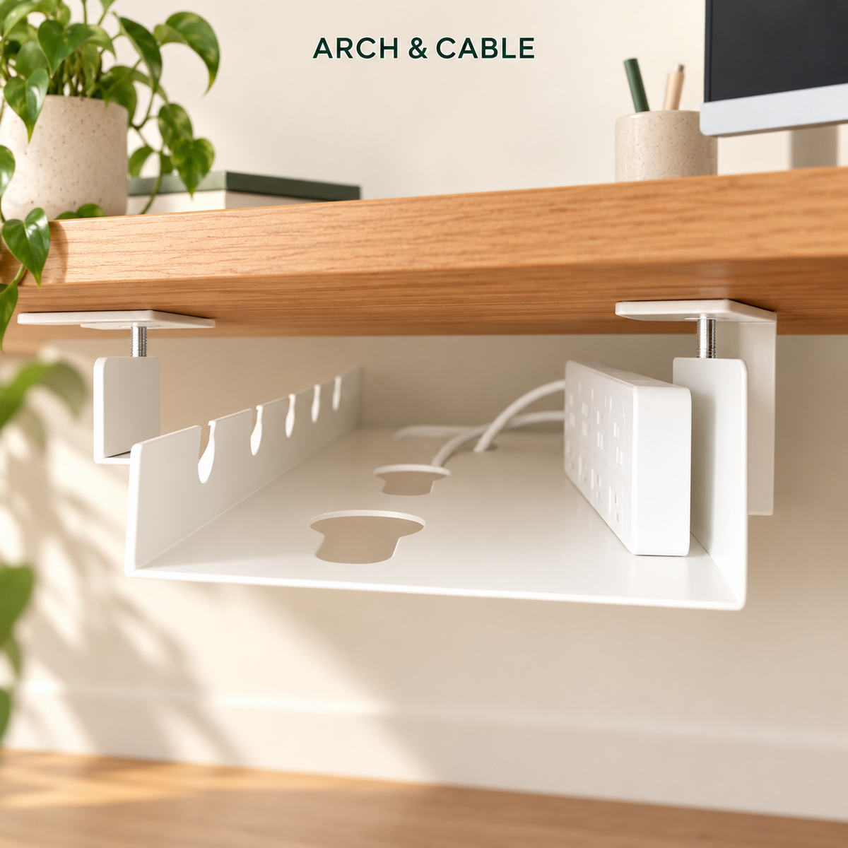 Panier blanc installé sous un bureau en bois, avec passages pour câbles.