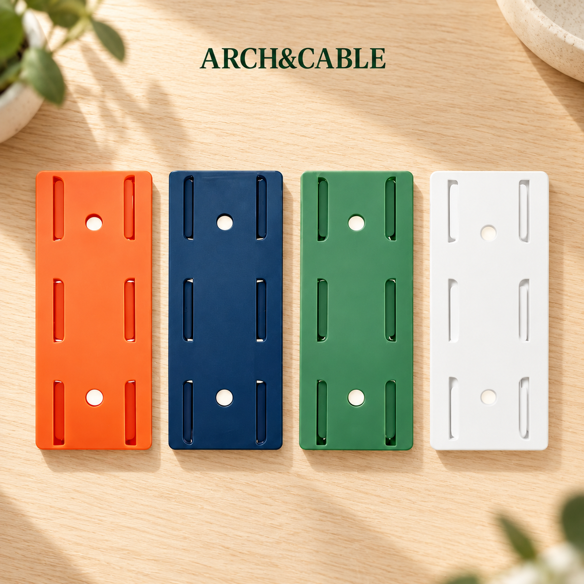 Supports adhésifs de multiprise orange, bleu, vert et blanc sur un bureau en bois clair.